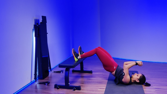A woman performing a hip thrust exercise on a bench, demonstrating proper form and technique.