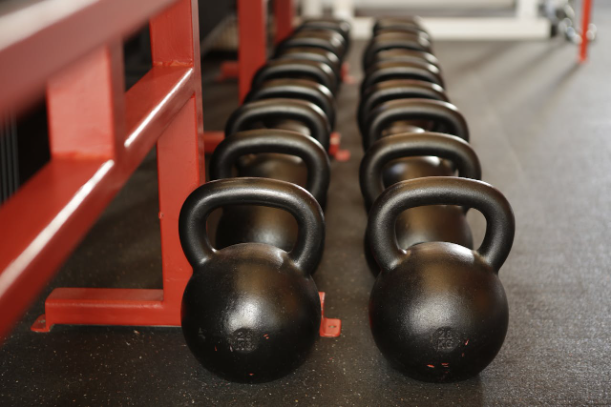 A row of kettlebells representing muscle mass training